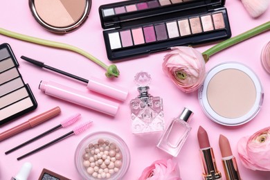 Flat lay composition with different makeup products and beautiful spring flowers on pink background