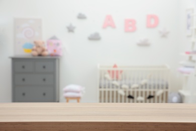 Photo of Empty wooden table in baby room. Space for text