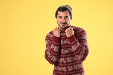 Photo of Portrait of young man in Christmas sweater and hat on yellow background