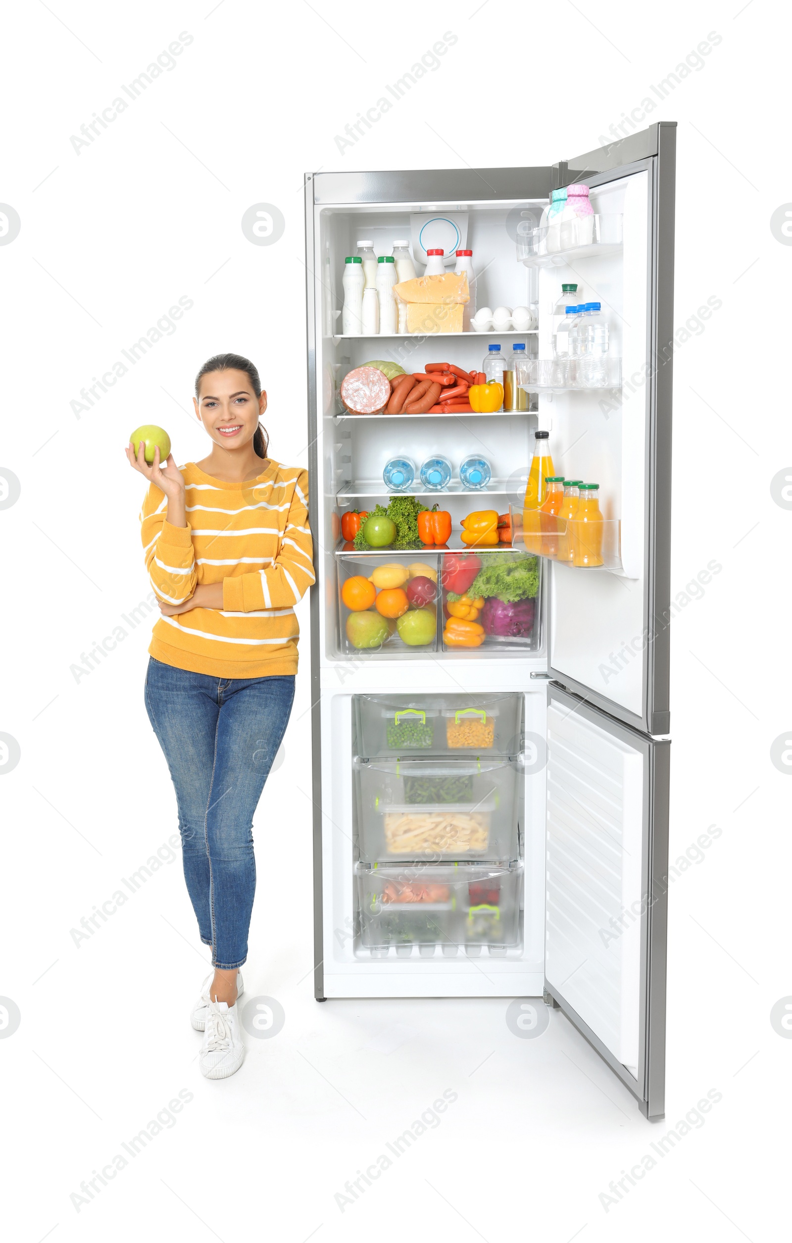 Photo of Young woman with apple near open refrigerator on white background