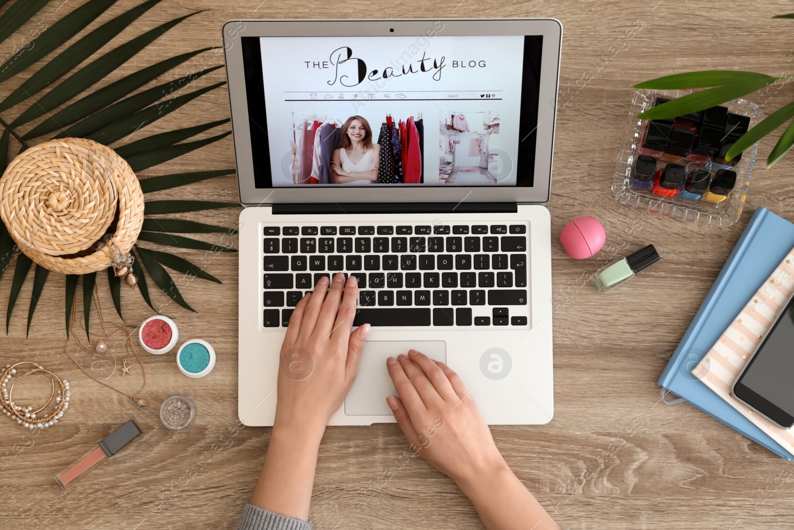 Photo of Woman working with beauty blogger site on laptop at table, top view
