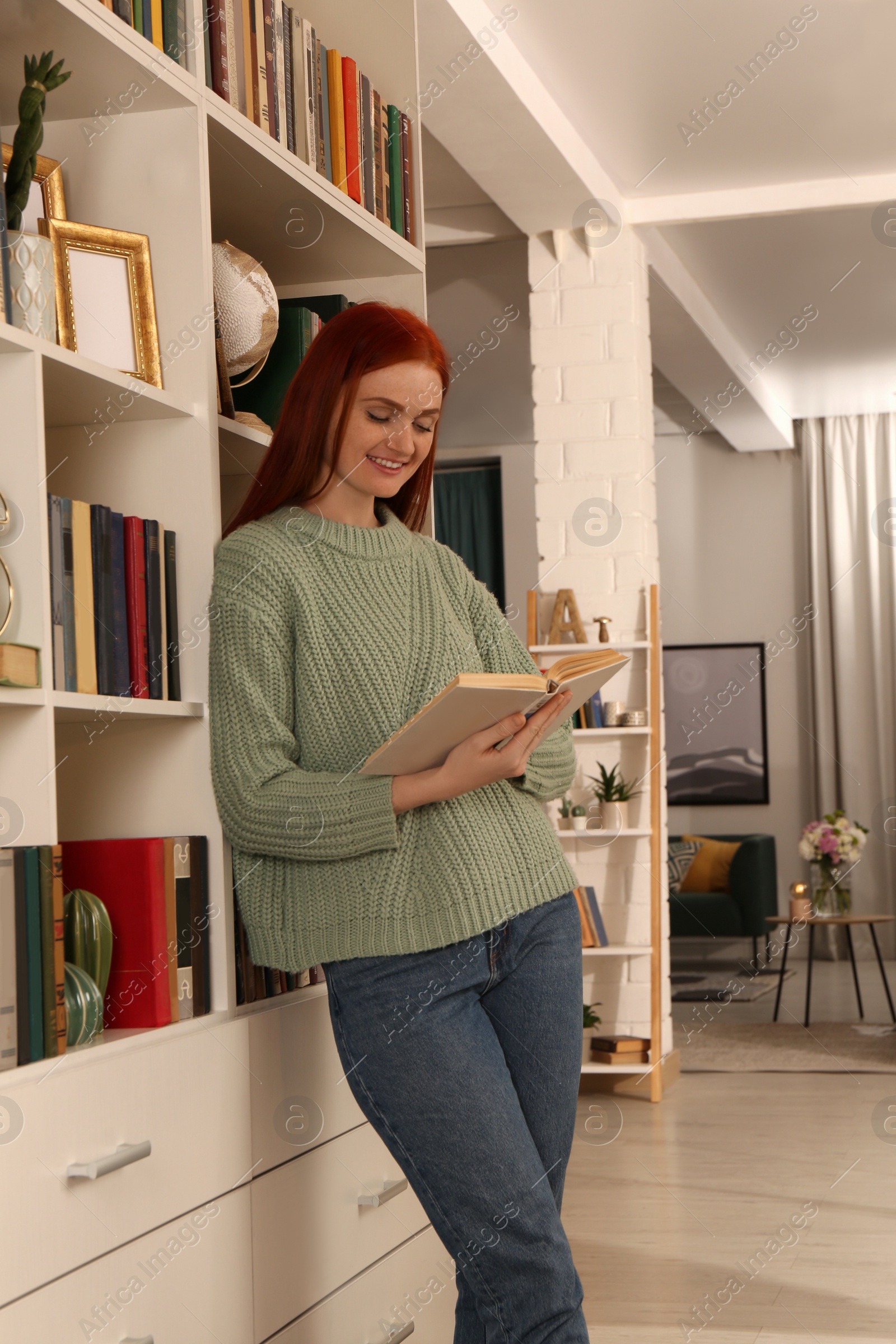 Photo of Beautiful young woman reading book in room. Home library