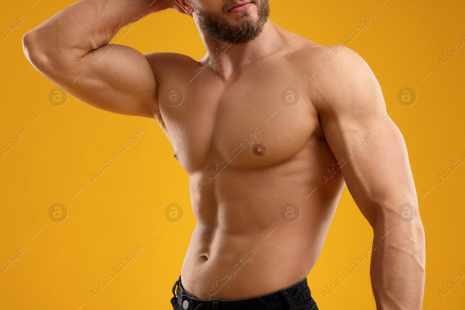 Photo of Muscular man showing abs on orange background, closeup. Sexy body