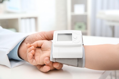 Photo of Doctor checking little girl's pulse with medical device in hospital, closeup