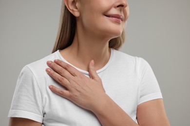 Mature woman with healthy skin on grey background, closeup