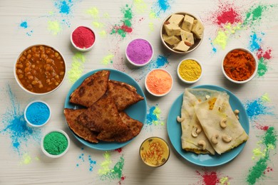 Photo of Traditional Indian food and color powders on white wooden table, flat lay. Holi festival celebration