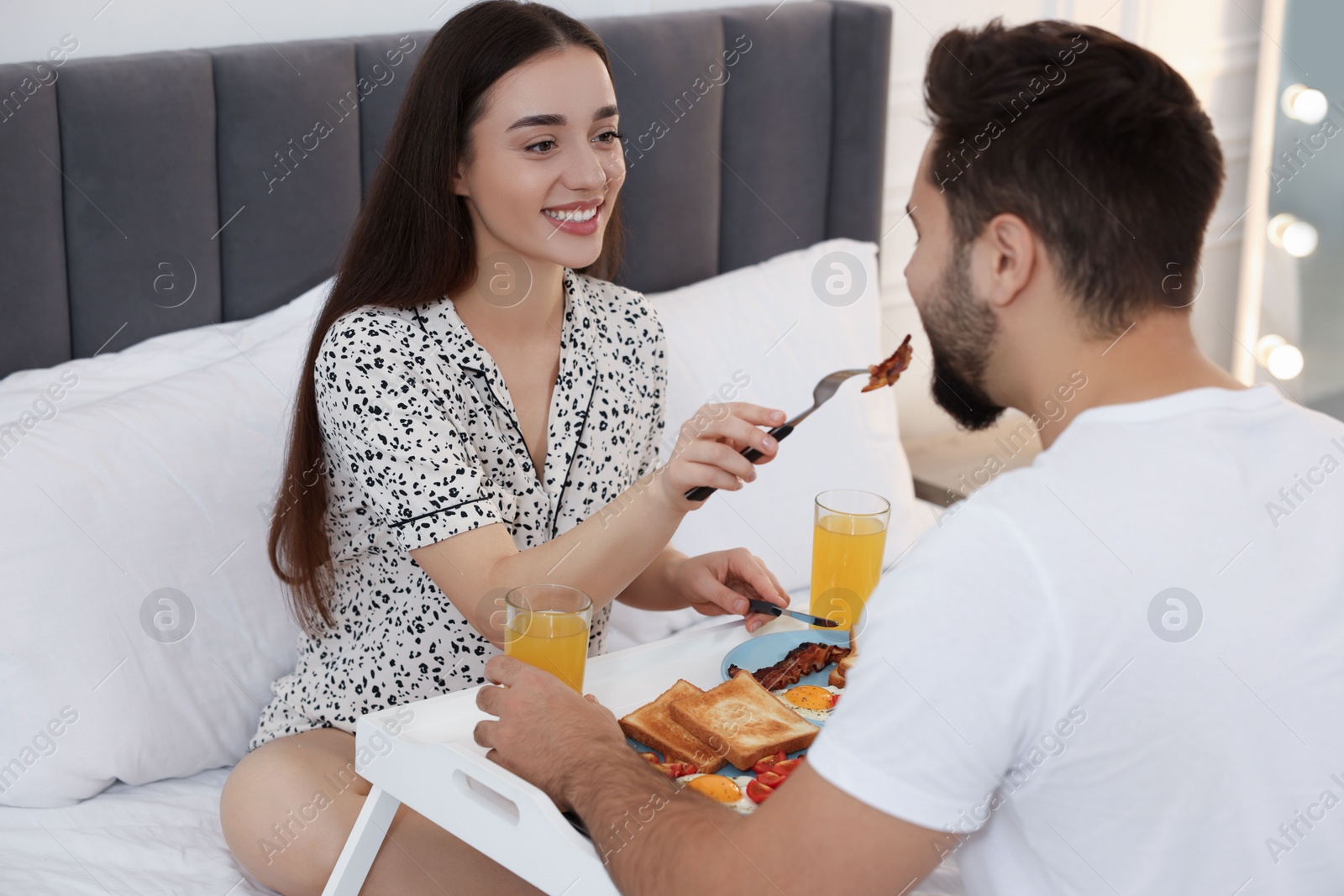 Photo of Happy couple having breakfast on bed at home