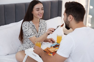 Happy couple having breakfast on bed at home