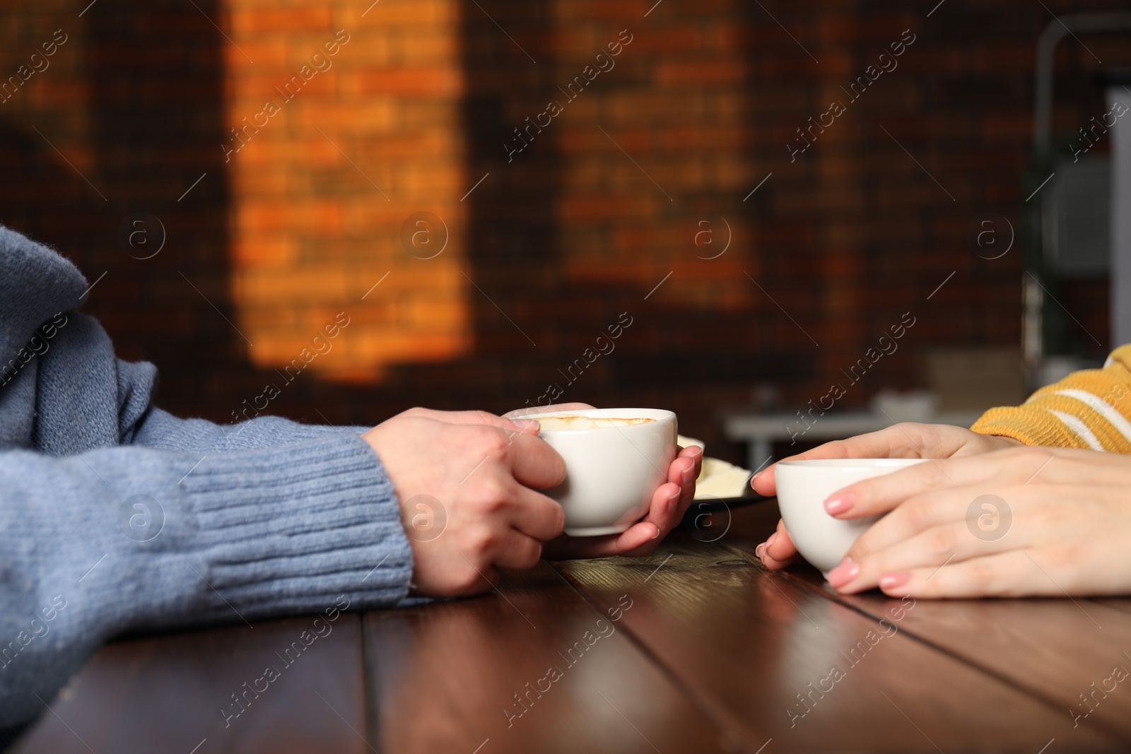 Photo of Women having coffee break at wooden table in cafe, closeup