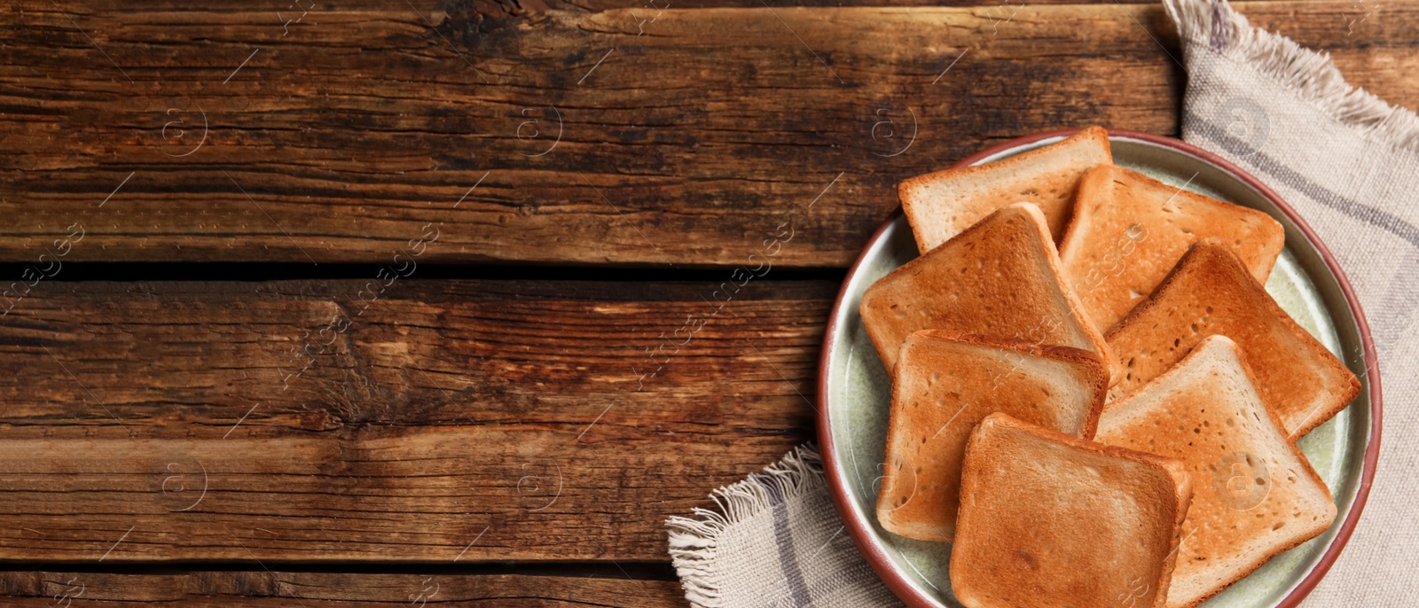 Image of Slices of tasty toasted bread on wooden table, top view with space for text. Banner design