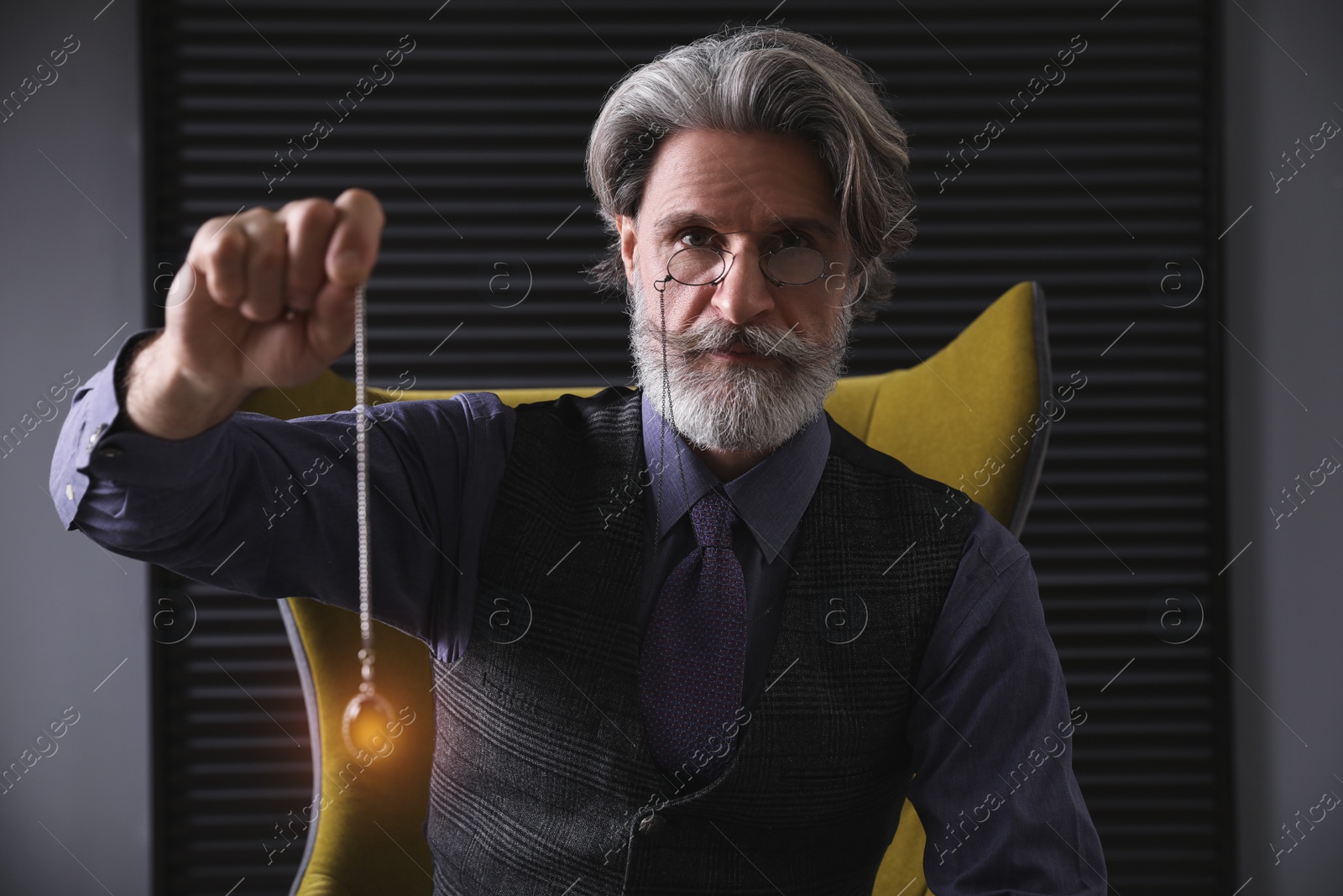 Photo of Psychotherapist with pendulum in office. Hypnotherapy session