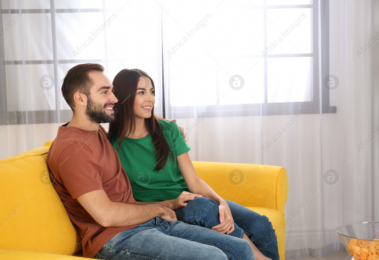 Photo of Young couple watching TV on sofa at home