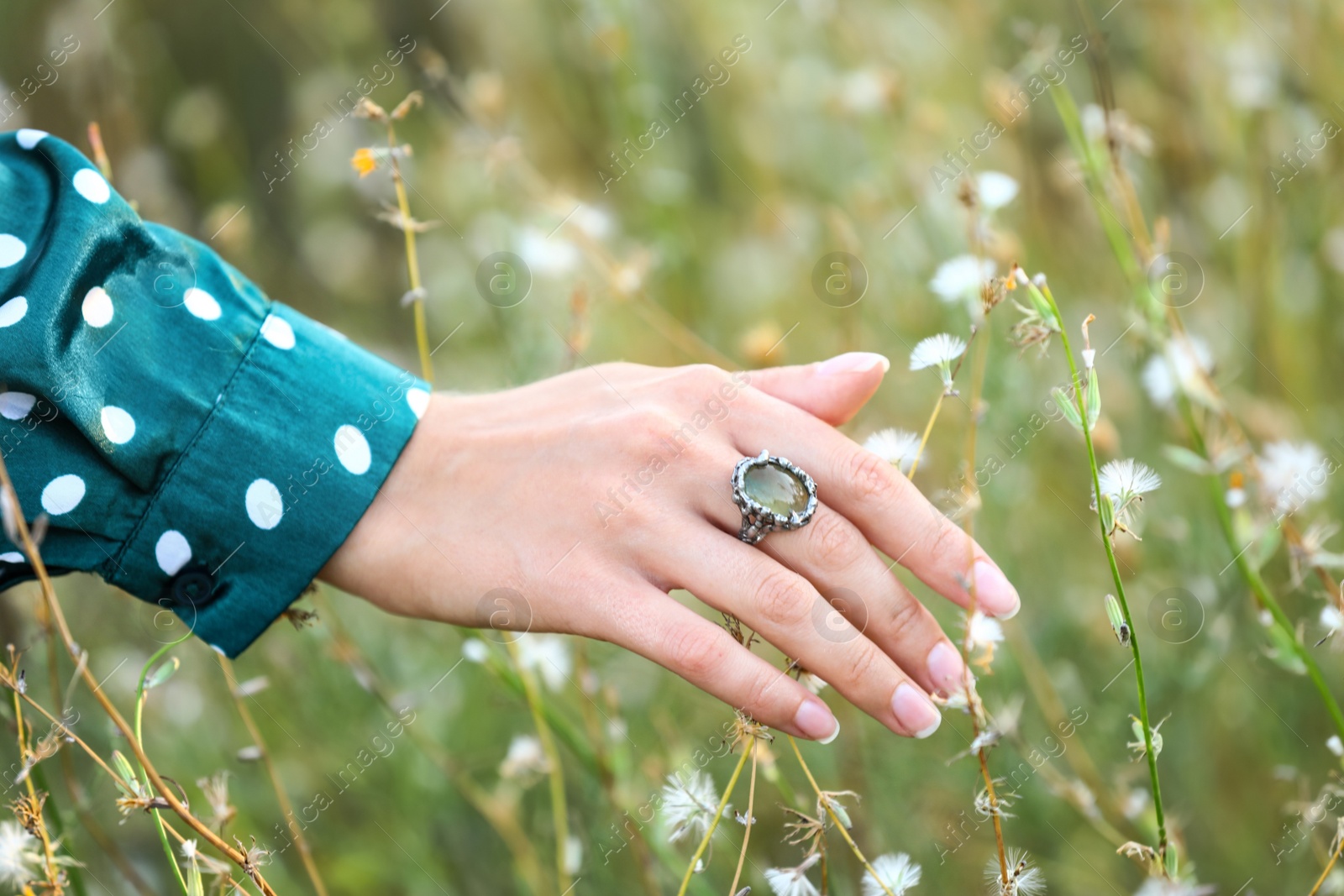 Photo of Young woman wearing beautiful silver ring with prehnite gemstone outdoors, closeup