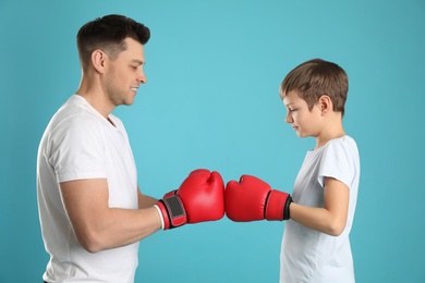 Photo of Dad and his son with boxing gloves on color background