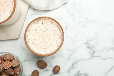 Glass of milk with nutmeg on white marble table, flat lay. Space for text