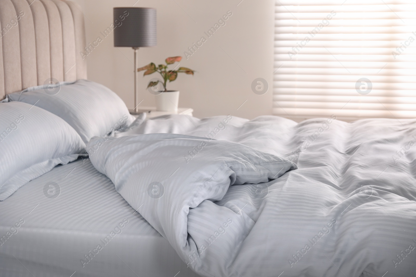 Photo of Comfortable bed with soft blanket near window indoors