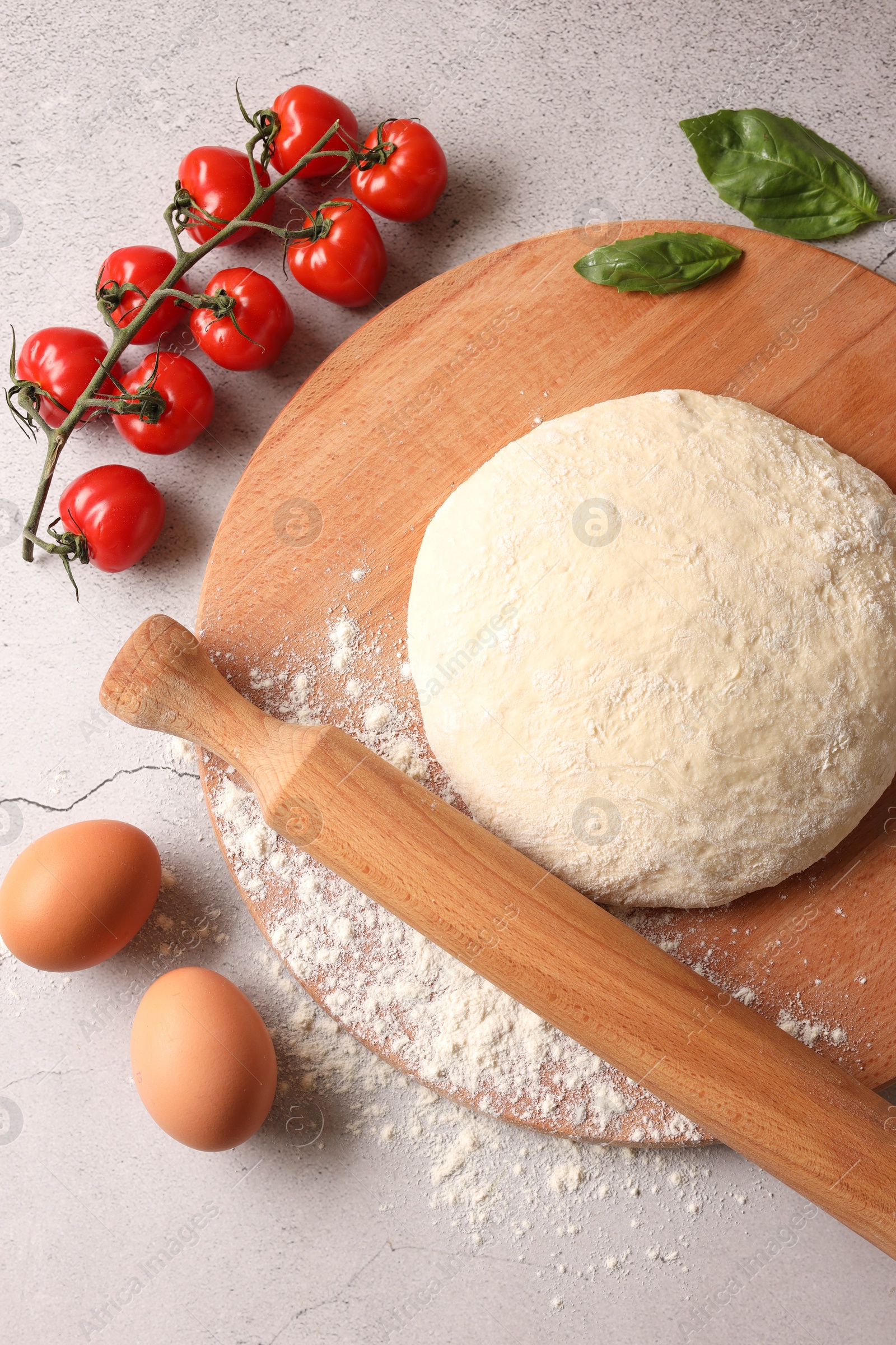 Photo of Pizza dough, products and rolling pin on gray textured table, flat lay