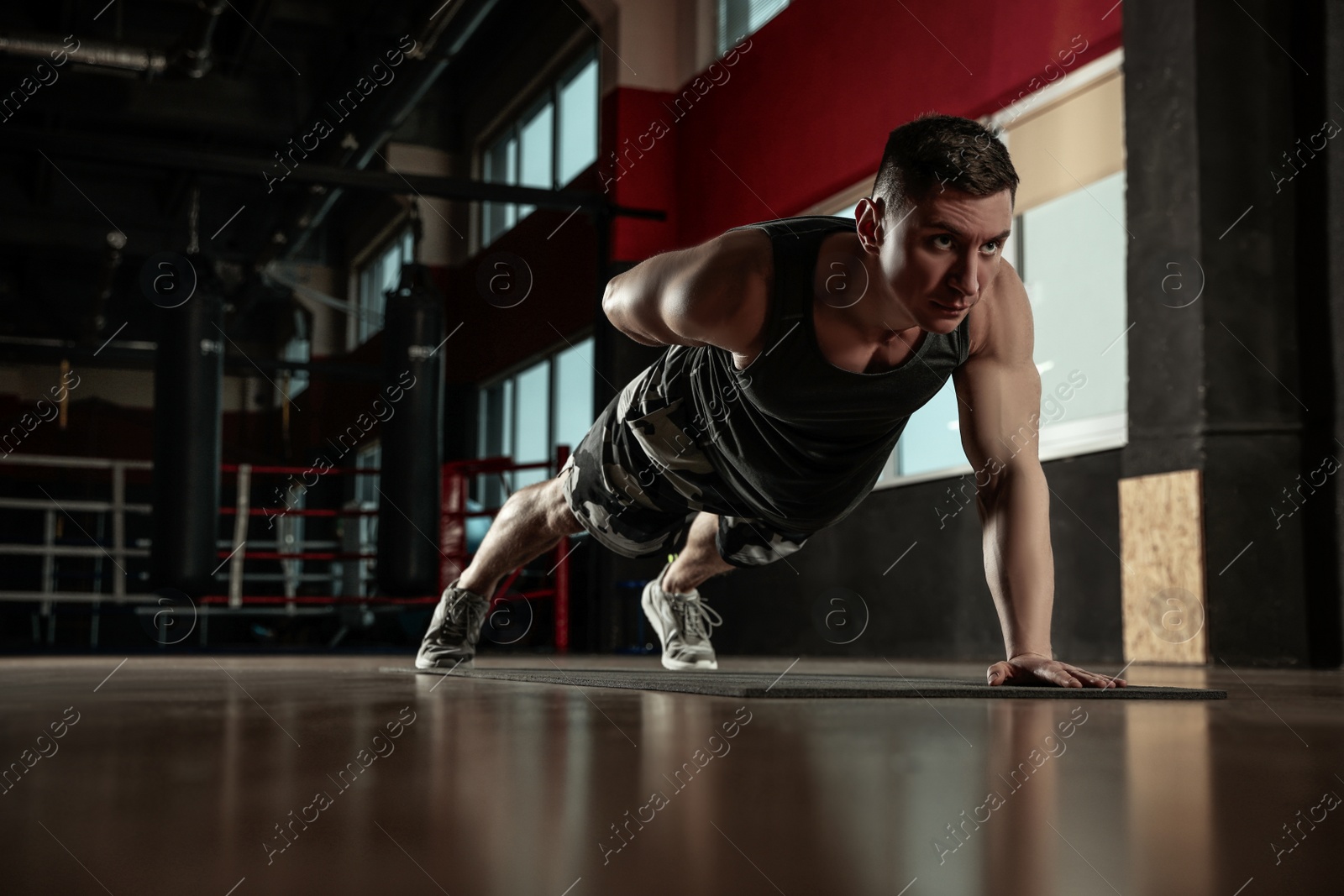 Photo of Man doing plank exercise in modern gym