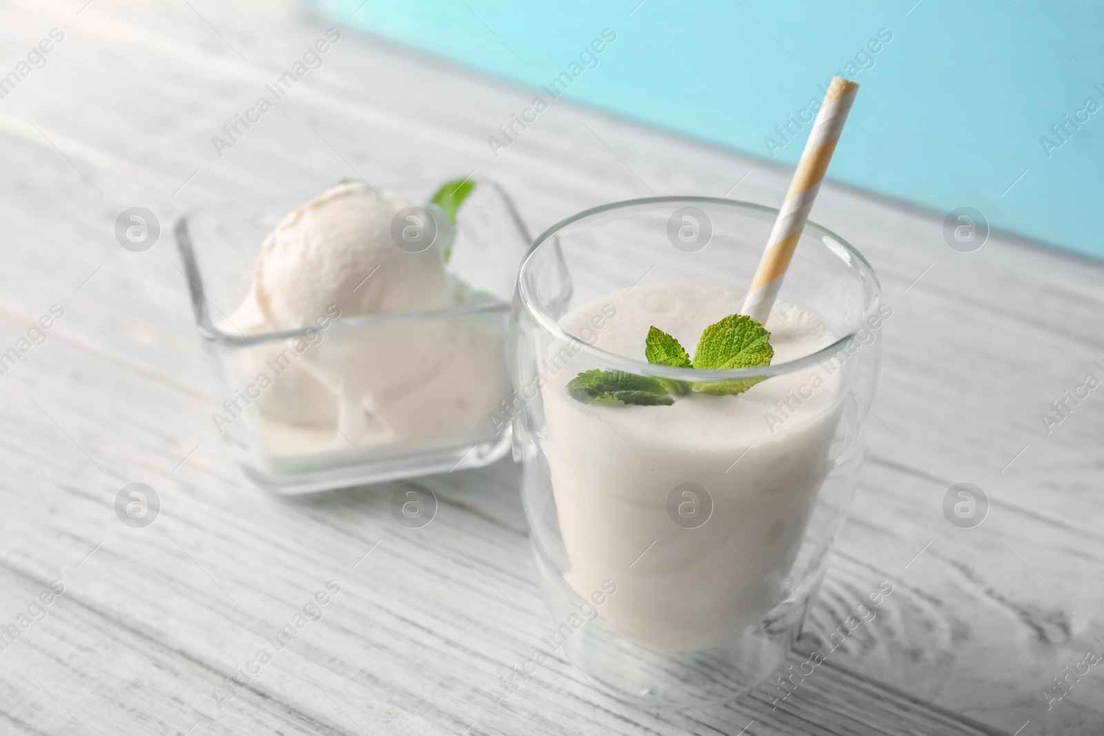 Photo of Glass with milk shake and tasty vanilla ice cream on wooden table