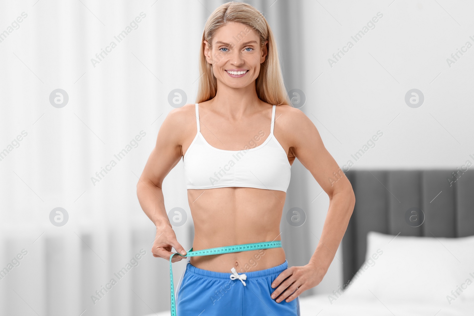 Photo of Slim woman measuring waist with tape at home. Weight loss
