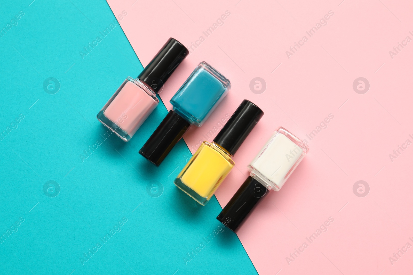 Photo of Bright nail polishes in bottles on color background, flat lay