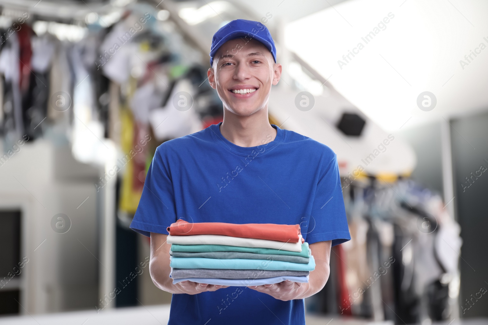 Image of Happy courier holding folded clothes in dry-cleaning