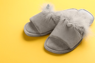 Photo of Pair of stylish soft slippers on yellow background