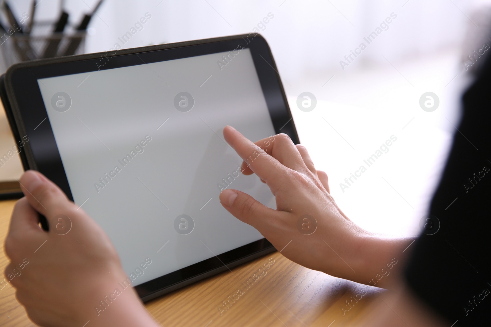 Photo of Woman working with modern tablet at wooden table, closeup. Space for design