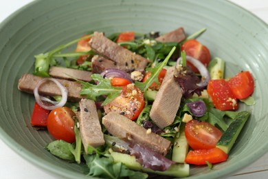 Photo of Delicious salad with beef tongue and vegetables in bowl, closeup