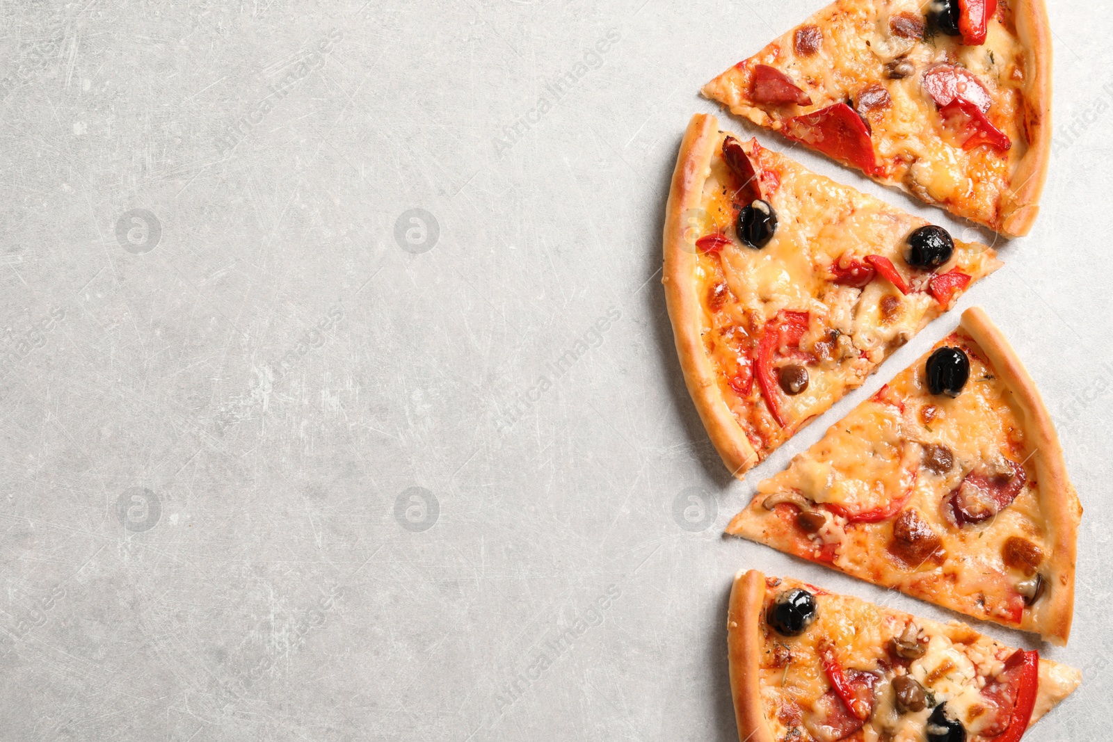 Photo of Slices of tasty pizza with olives and sausages on gray table