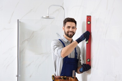 Photo of Handyman working with building level in bathroom. Professional construction tools