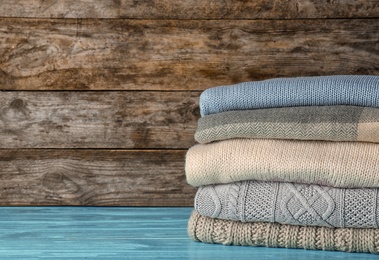 Photo of Stack of warm autumn clothes on table. Space for text