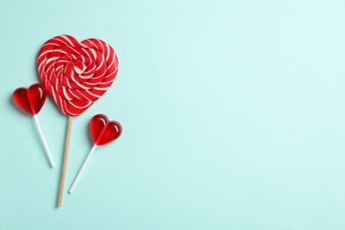 Photo of Sweet heart shaped lollipops on light blue background, flat lay with space for text. Valentine's day celebration