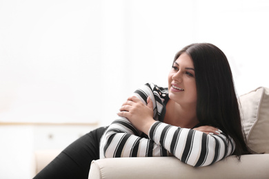 Beautiful overweight woman on sofa in living room. Plus size model