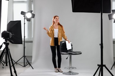 Photo of Casting call. Young woman with script performing on grey background in modern studio