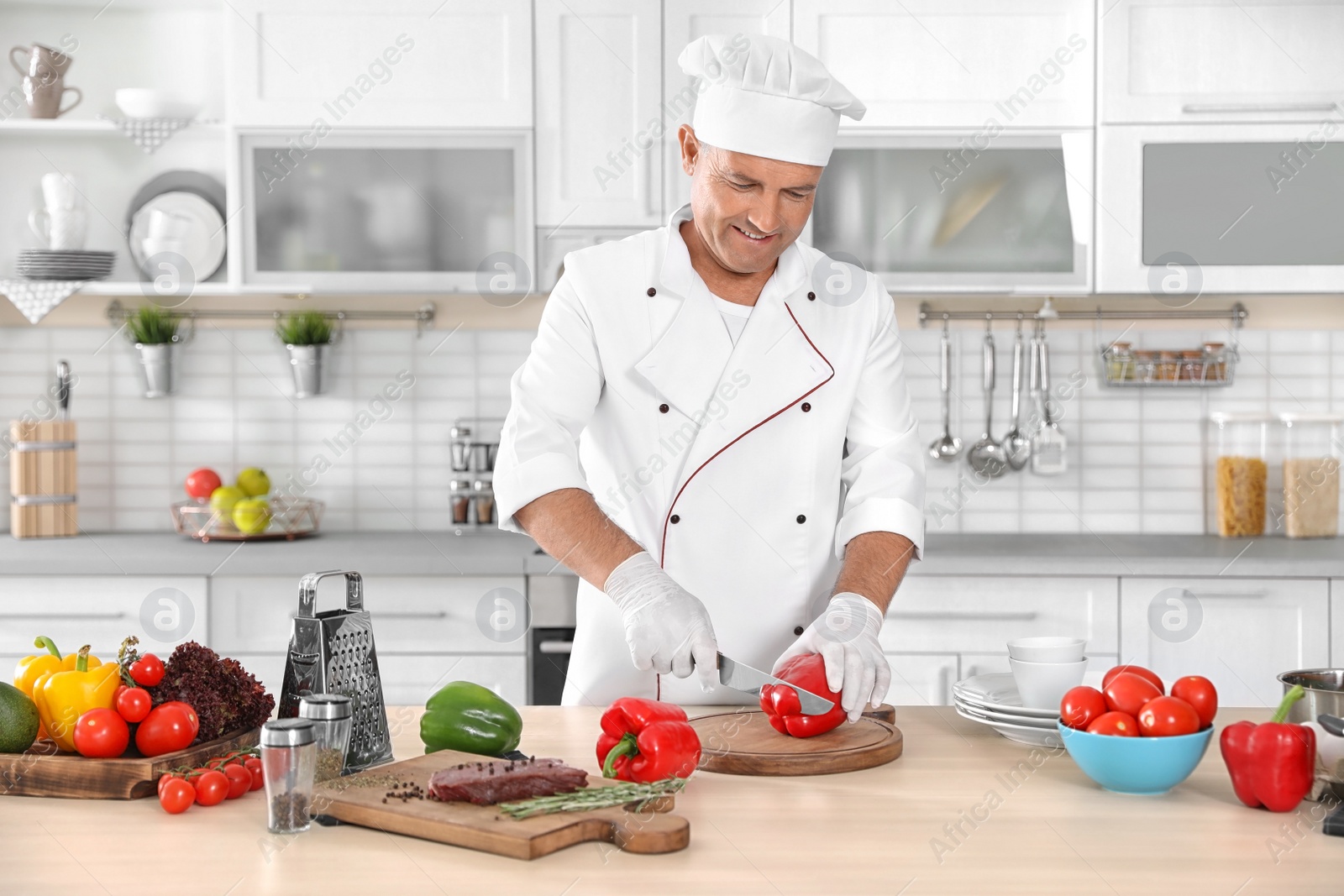 Photo of Professional chef cutting pepper on table in kitchen