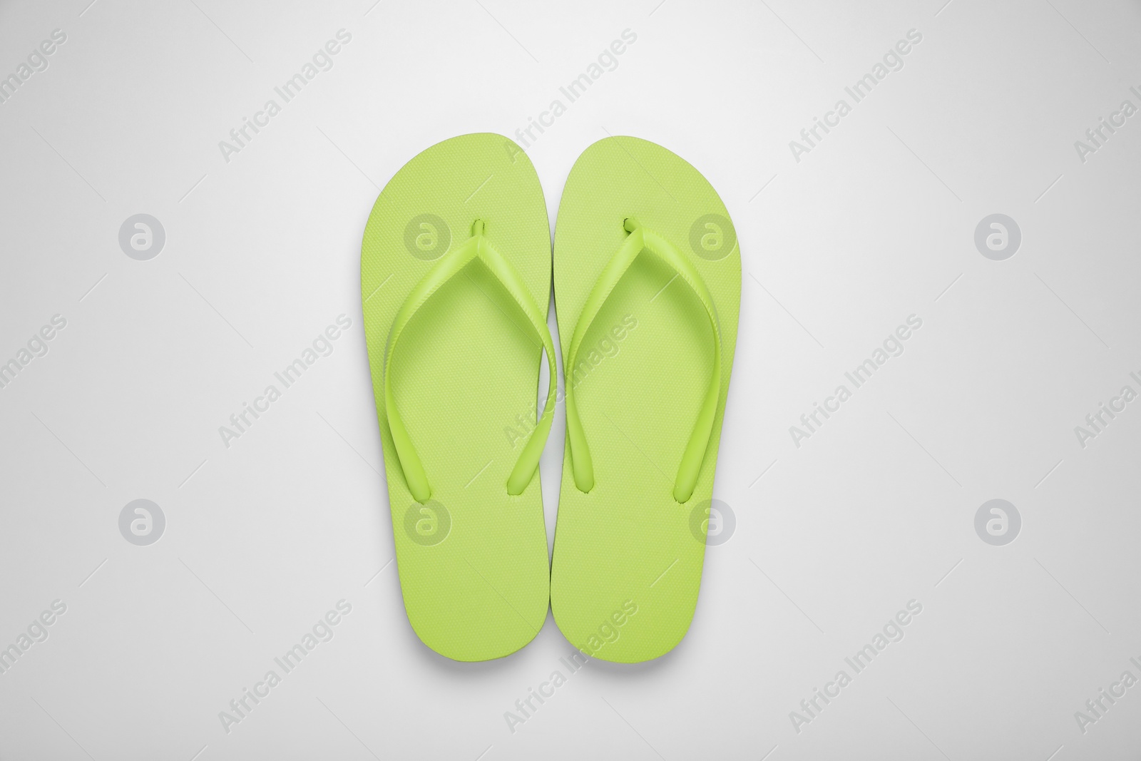 Photo of Light green flip flops on white background, top view