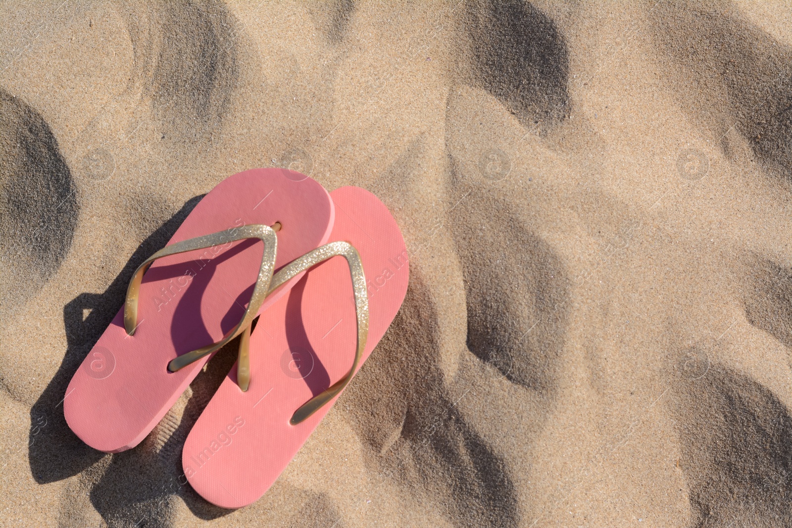 Photo of Stylish flip flops on sandy beach, flat lay. Space for text