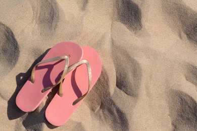 Stylish flip flops on sandy beach, flat lay. Space for text