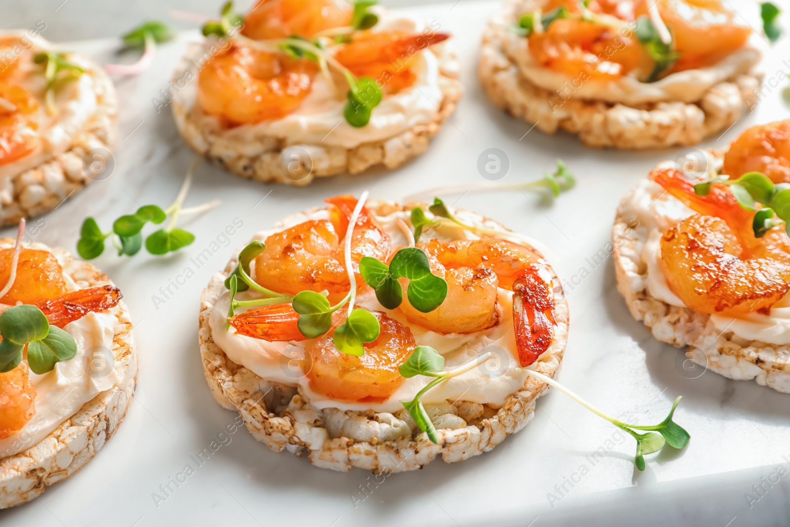 Photo of Delicious small sandwiches with shrimps on marble board