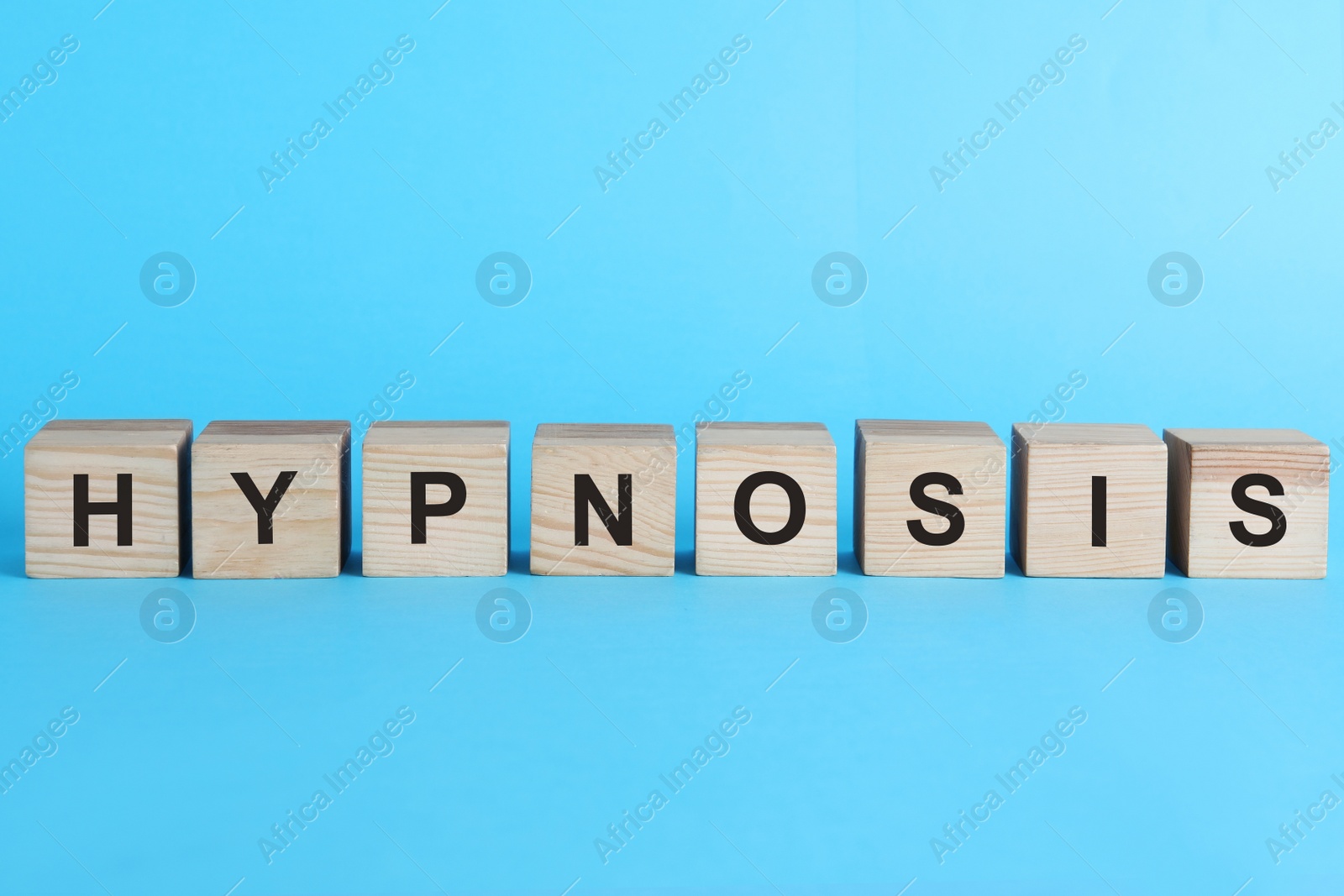 Photo of Wooden blocks with word HYPNOSIS on light blue background