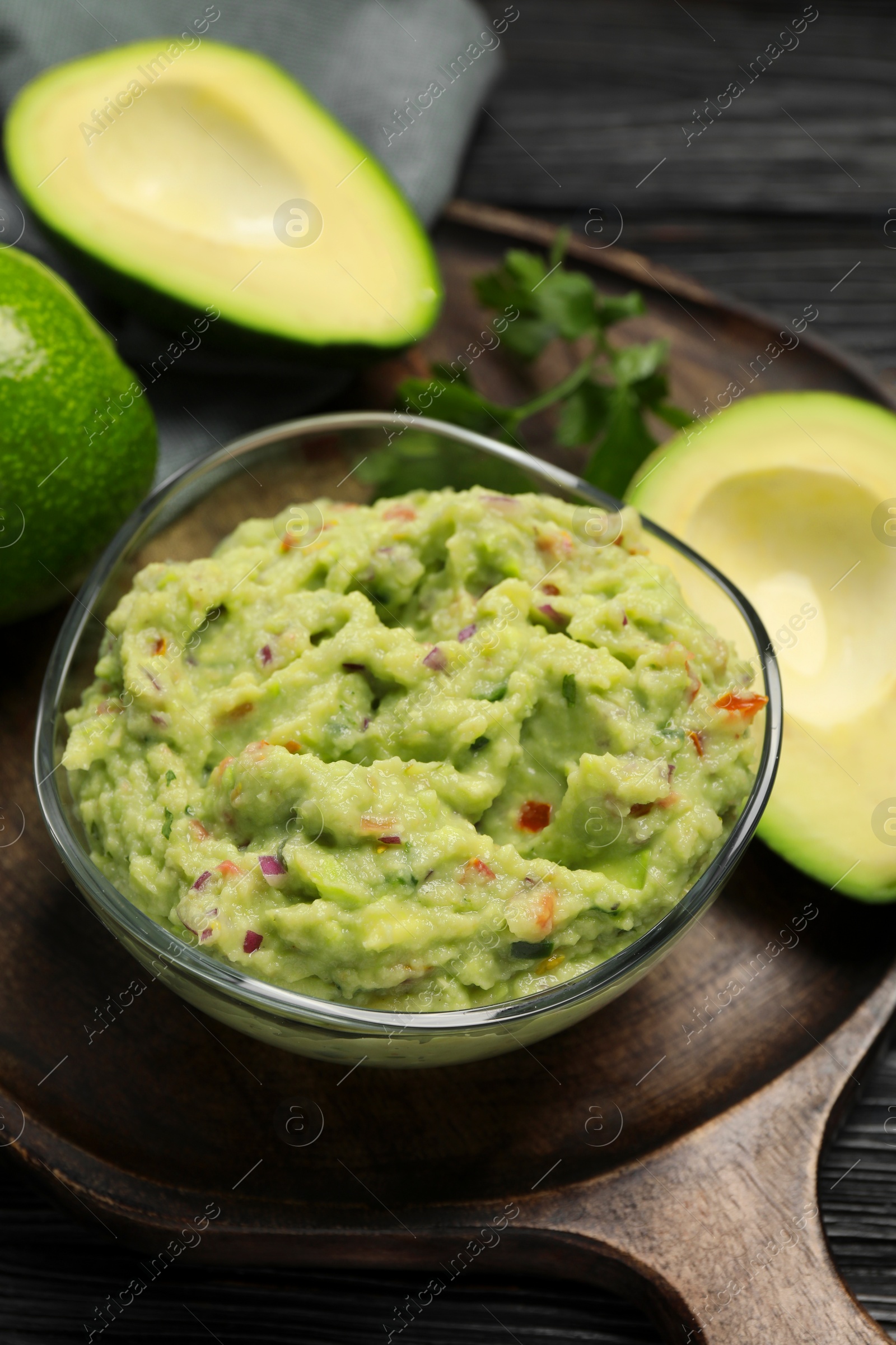 Photo of Delicious guacamole with parsley and fresh avocado on wooden board