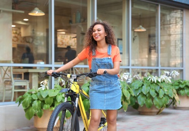 Beautiful young African-American woman with bicycle on city street