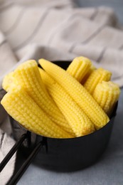 Photo of Tasty fresh yellow baby corns in dish on grey table, closeup