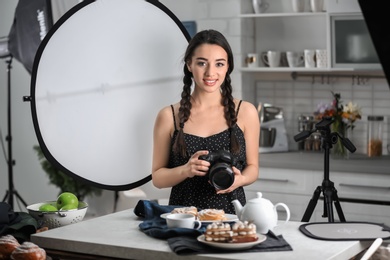 Photo of Young woman with professional camera in photo studio