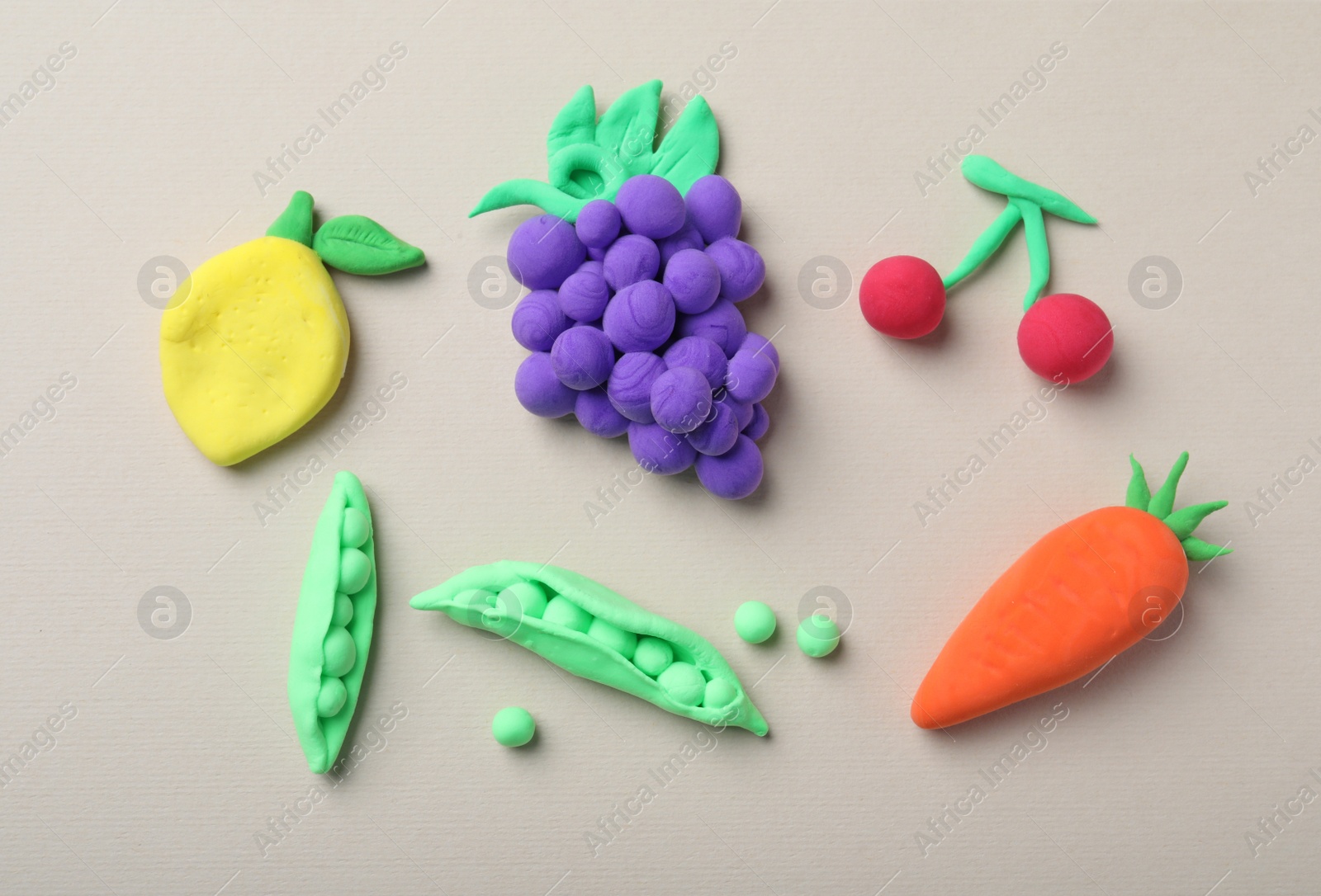 Photo of Different fruits and vegetables made from play dough on light grey background, flat lay