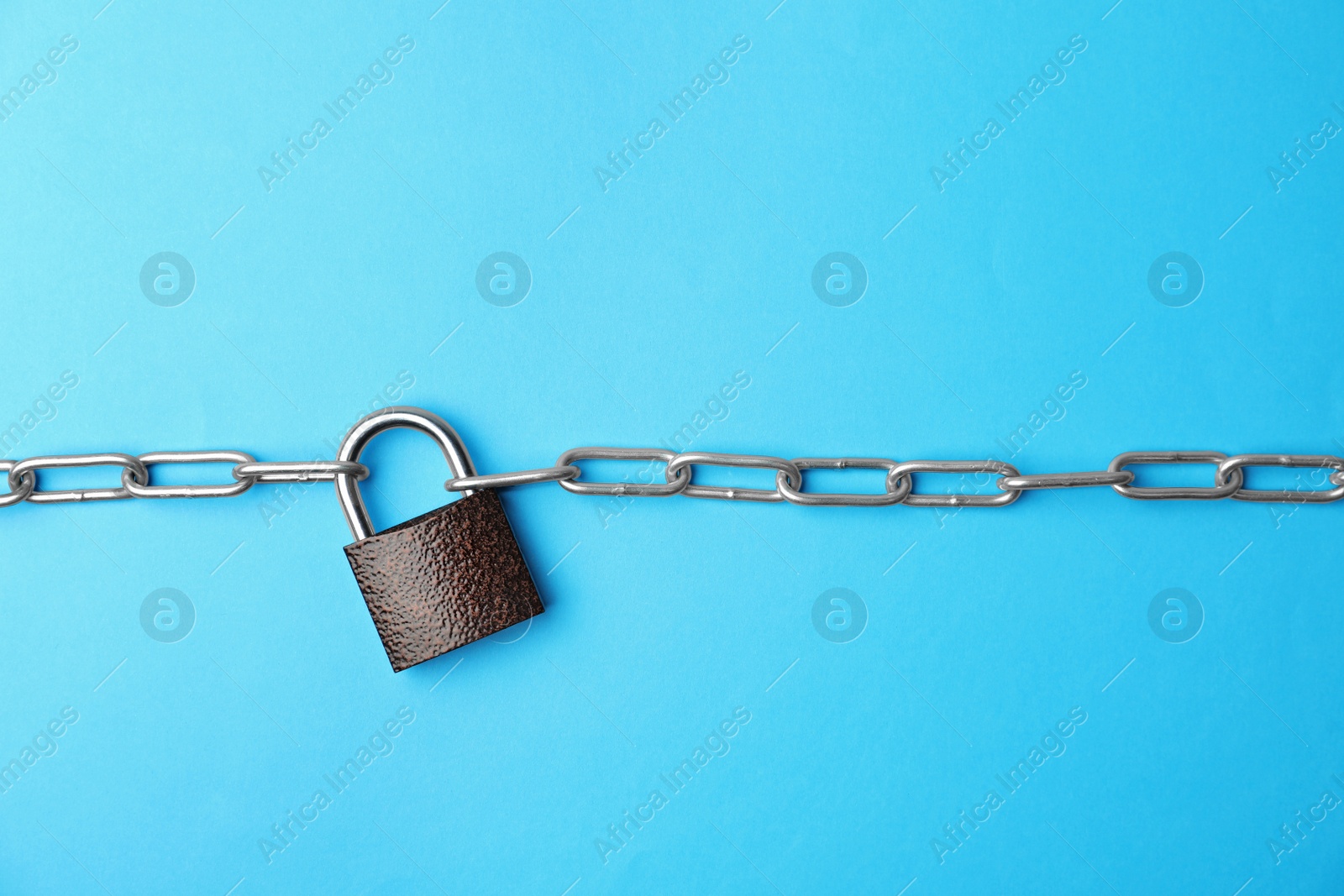 Photo of Steel padlock and chain on light blue background, top view. Safety concept