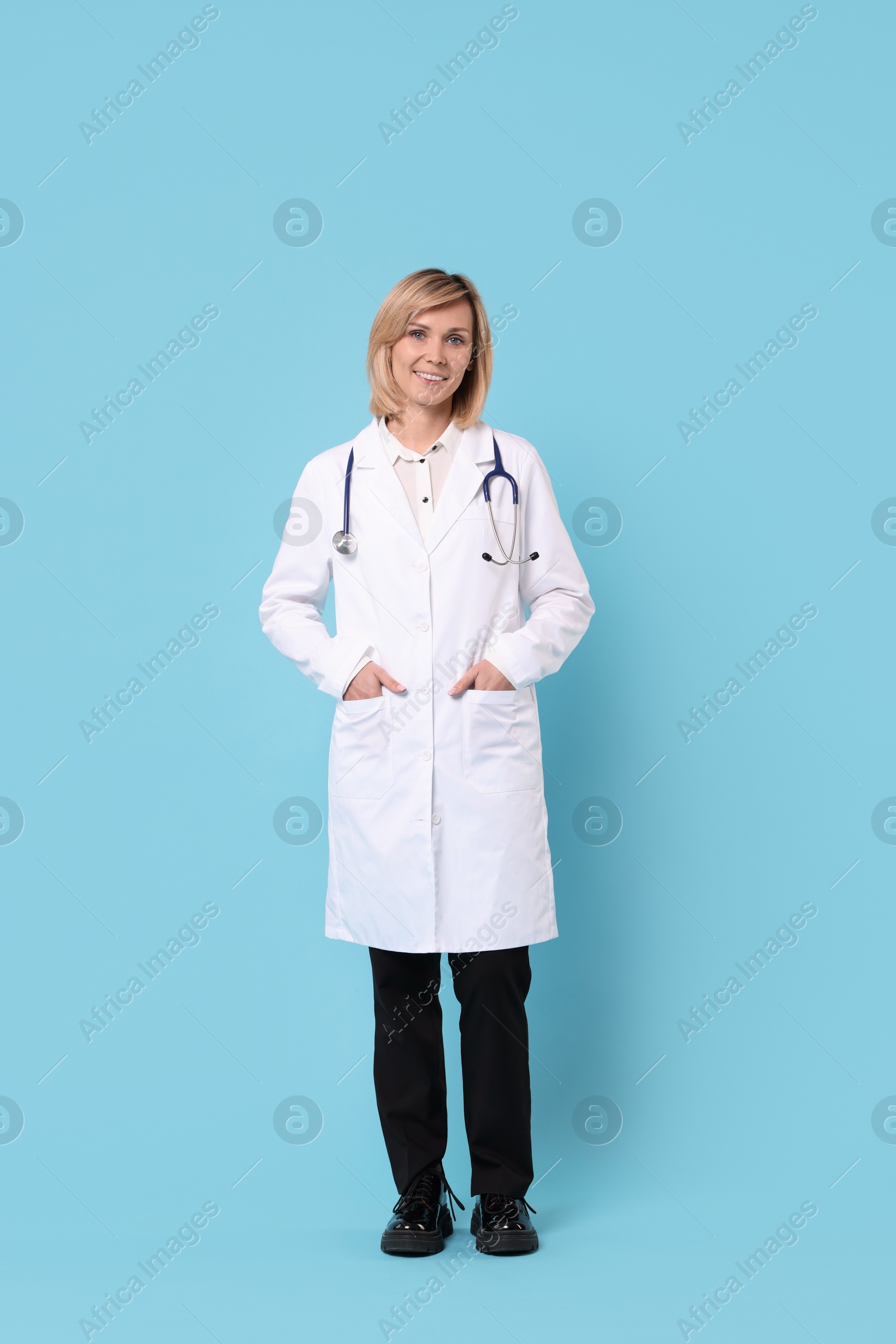 Photo of Smiling doctor in uniform on light blue background