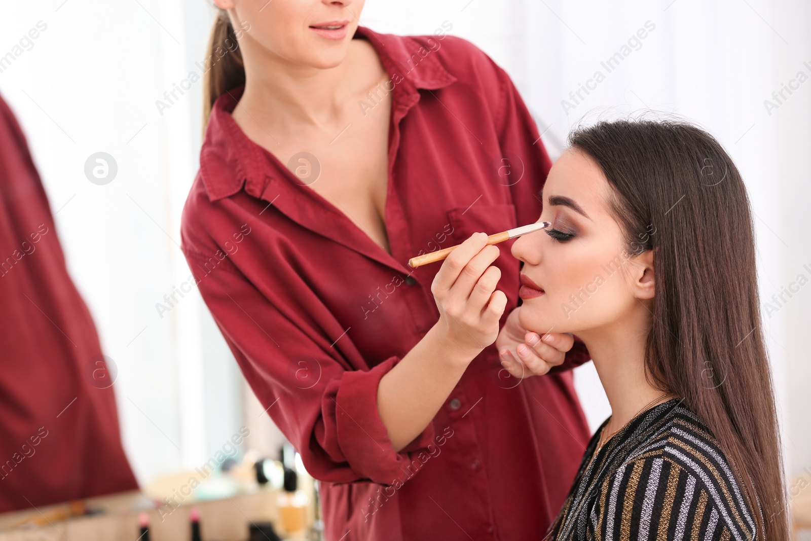 Photo of Professional visage artist applying makeup on woman's face in salon