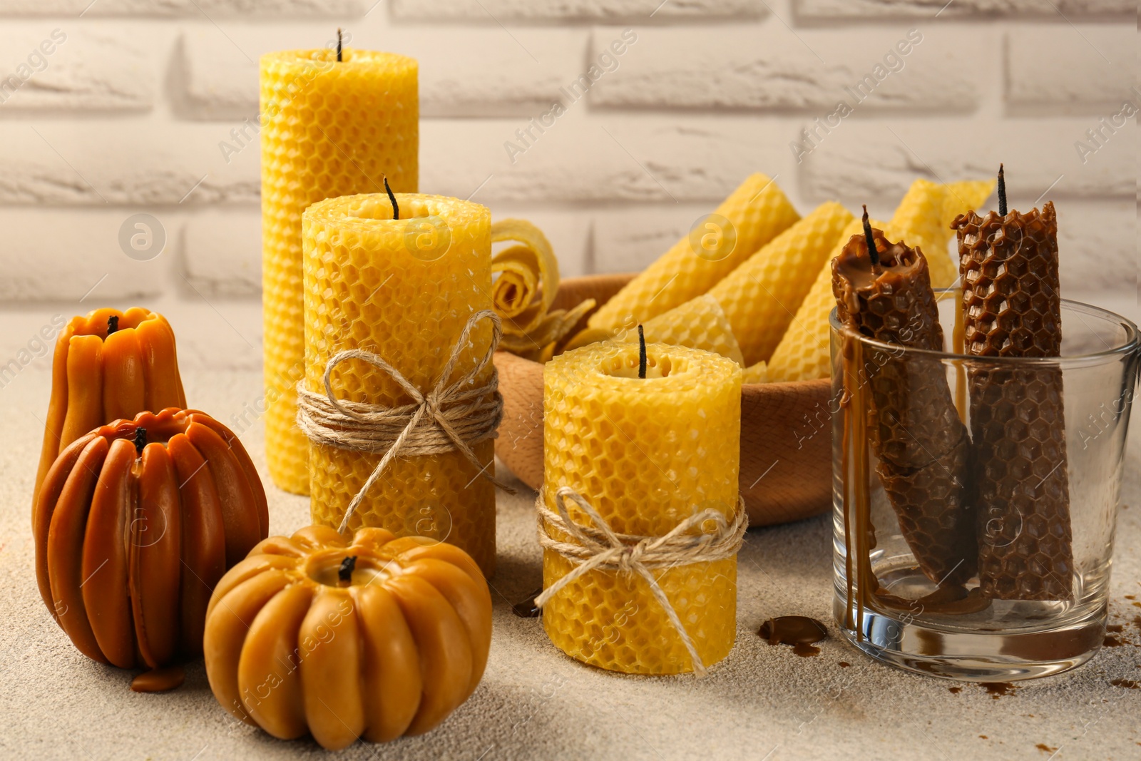 Photo of Beautiful different beeswax candles on light textured table